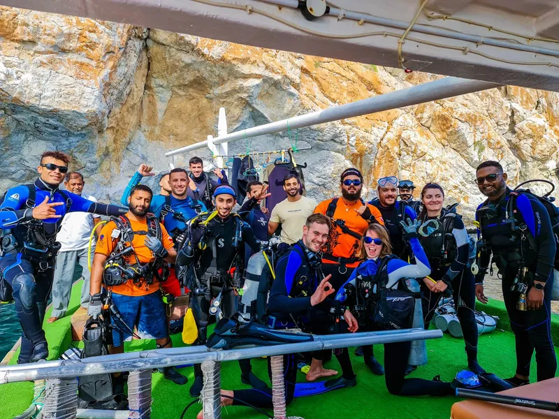 Groupe de plongeurs souriants posant sur un bateau de plongée ensoleillé