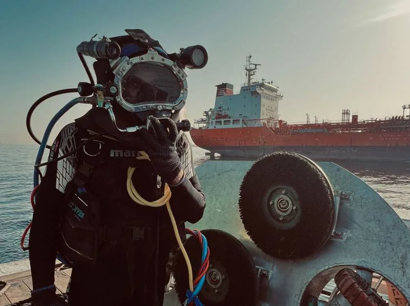Plongeur en équipement complet près d'un grand navire en mer