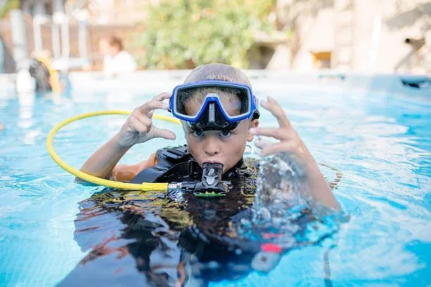 Jeune plongeur en formation, équipé, dans une piscine bleue claire