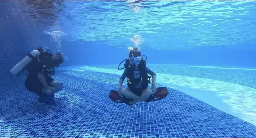 Deux plongeurs en formation dans une piscine, position assise