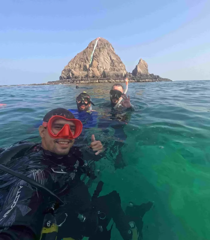 Trois plongeurs souriants avec masque et tuba en mer turquoise
