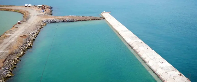 Quai en béton s'avançant dans une mer turquoise et calme
