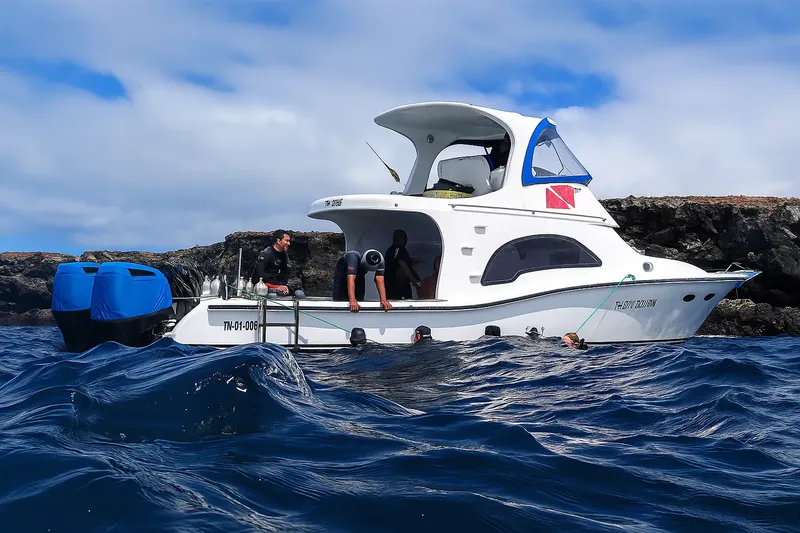 Bateau de plongée blanc avec passagers et équipement sur l'eau bleue