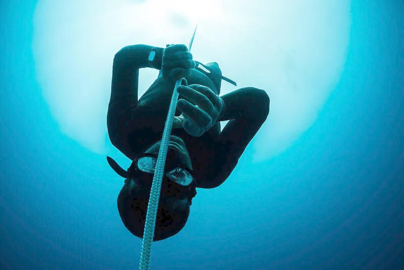 Apnée : un plongeur en combinaison descend le long d'un cordage