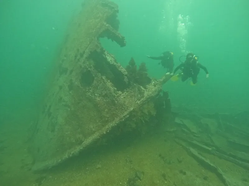 Deux plongeurs explorent l'épave d'un navire sous-marin, eau verte