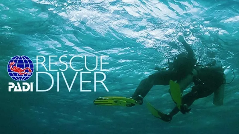 Plongeur en formation Rescue Diver nageant dans une eau turquoise claire