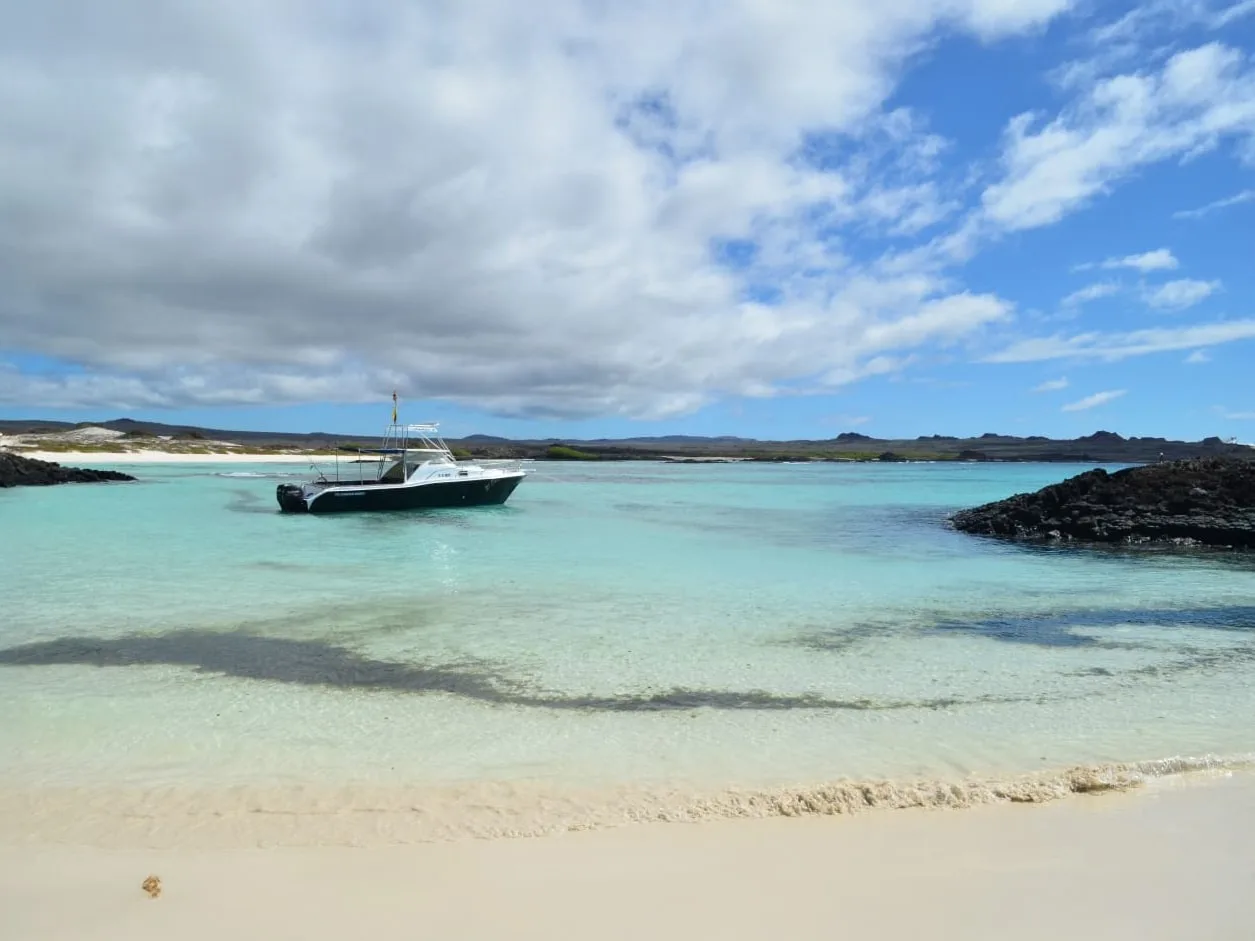 Bateau de plongée amarré dans une eau turquoise peu profonde sur plage