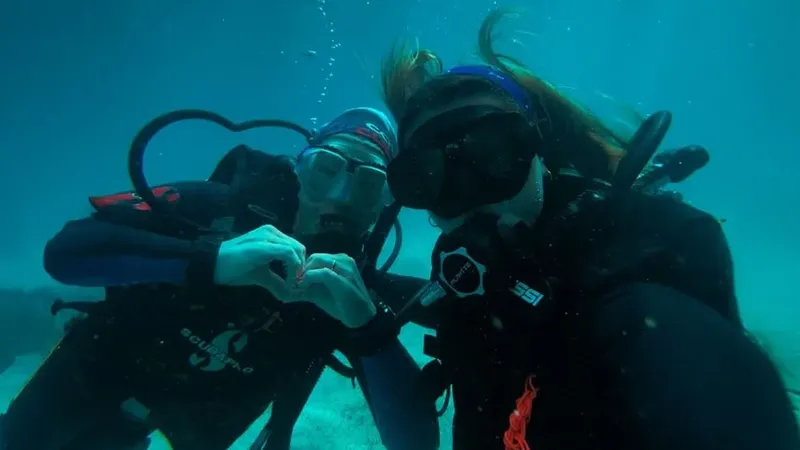 Deux plongeurs souriants font un signe en forme de coeur sous l'eau