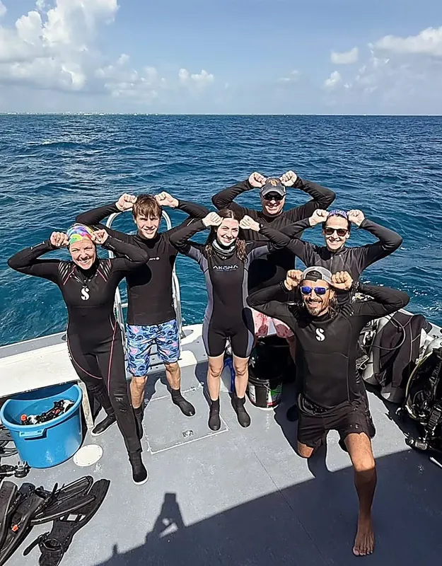 Groupe de plongeurs souriants sur le pont d'un bateau en mer