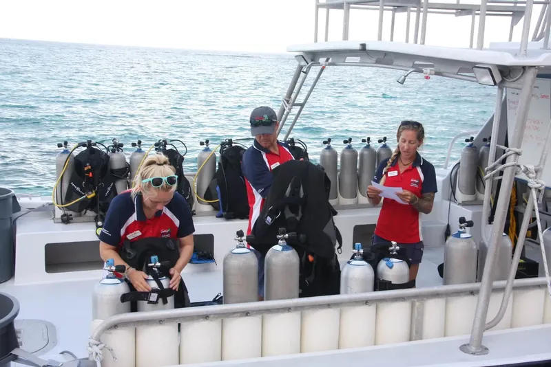 Trois personnes préparent du matériel de plongée sur un bateau en mer