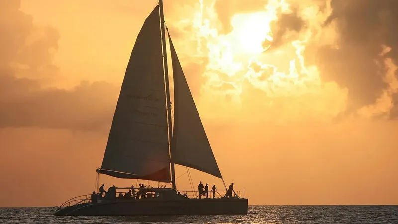 Catamaran à voile au coucher du soleil avec des passagers à bord