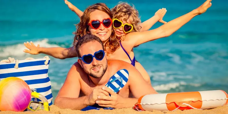 Famille souriante sur la plage avec lunettes de soleil et bouée