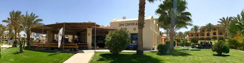 Façade d'un centre de plongée avec des palmiers et des personnes
