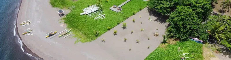 Bateaux de plongée et matériel sur une plage de sable sombre