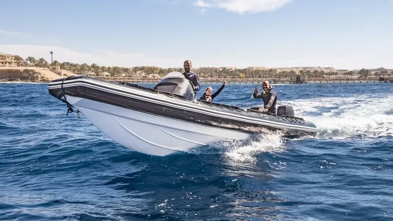 Trois personnes souriantes à bord d'un bateau semi-rigide en mer