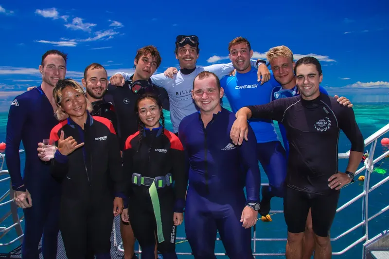 Groupe de plongeurs souriants posant sur le pont d'un bateau