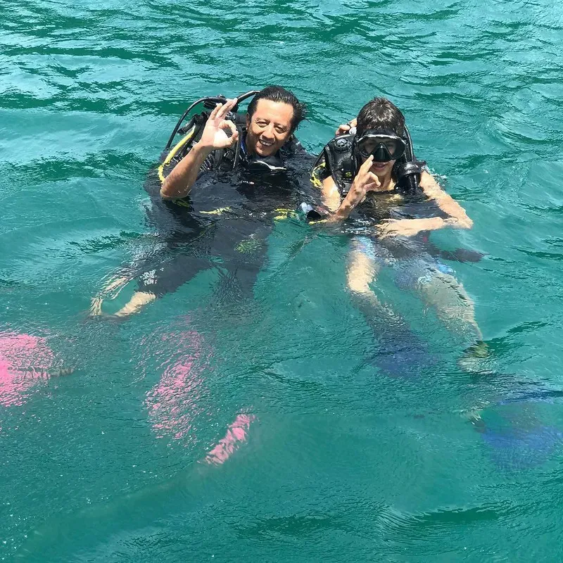 Deux plongeurs souriants flottent à la surface de l'eau turquoise