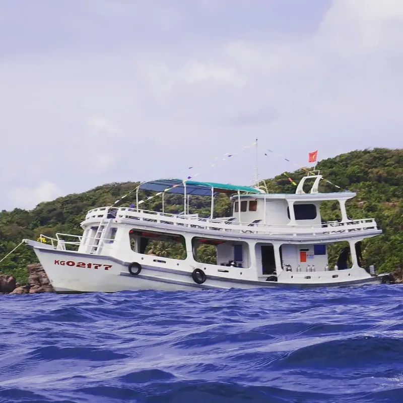 Bateau de plongée blanc sur l'eau bleue avec une île verte