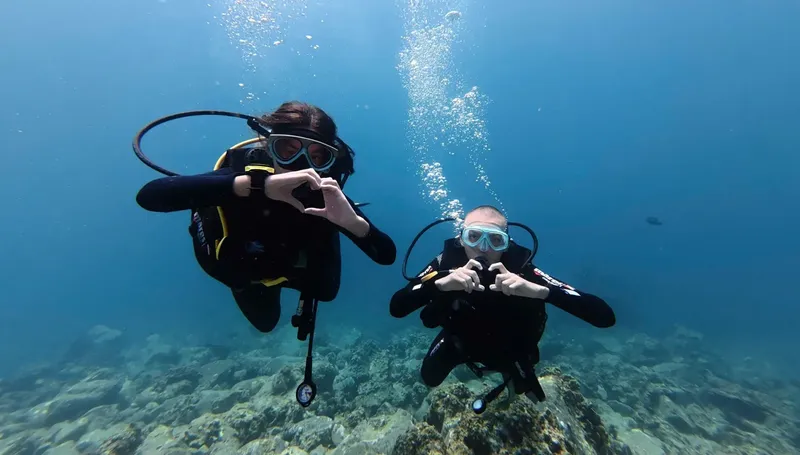 Deux plongeurs souriants forment un cœur avec leurs mains sous l'eau
