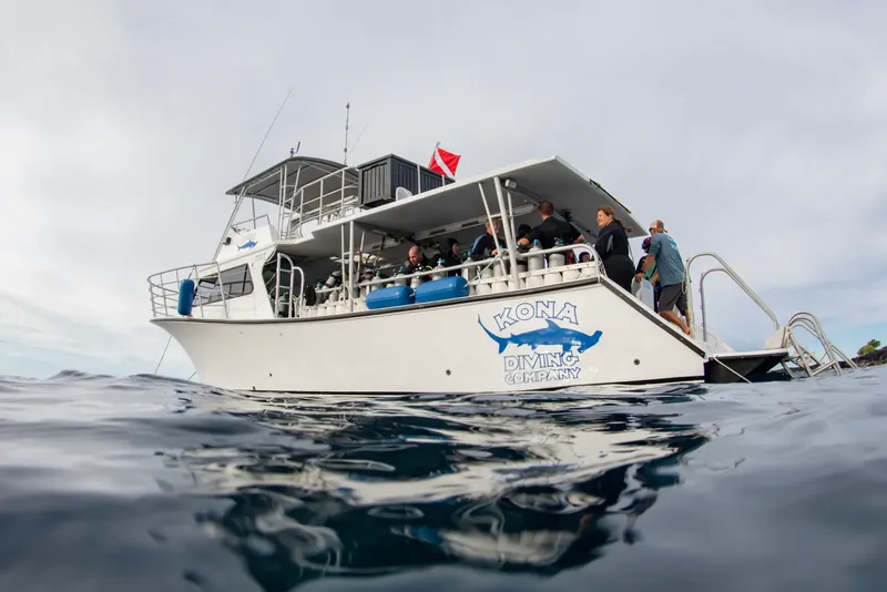 Bateau de plongée blanc avec des plongeurs et des bouteilles à bord