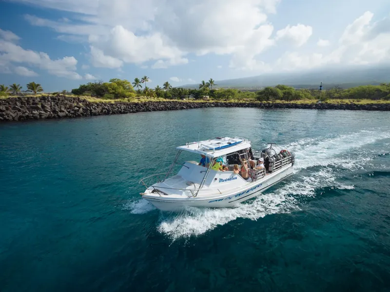 Bateau de plongée blanc navigue sur une eau turquoise ensoleillée