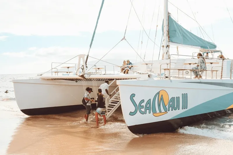 Catamaran blanc avec des passagers montant à bord sur une plage