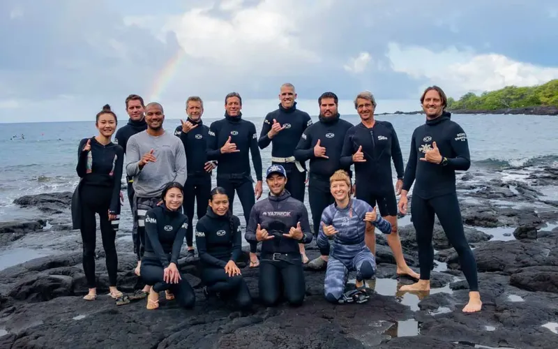 Groupe de personnes souriantes en combinaison de plongée sur des rochers