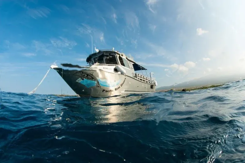 Bateau de plongée flottant sur l'océan bleu sous un ciel nuageux