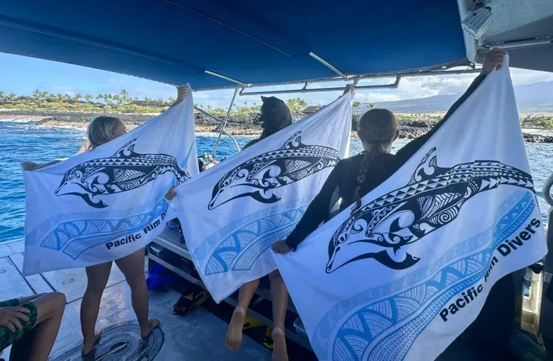 Trois personnes sur un bateau brandissent des drapeaux avec des motifs de baleines