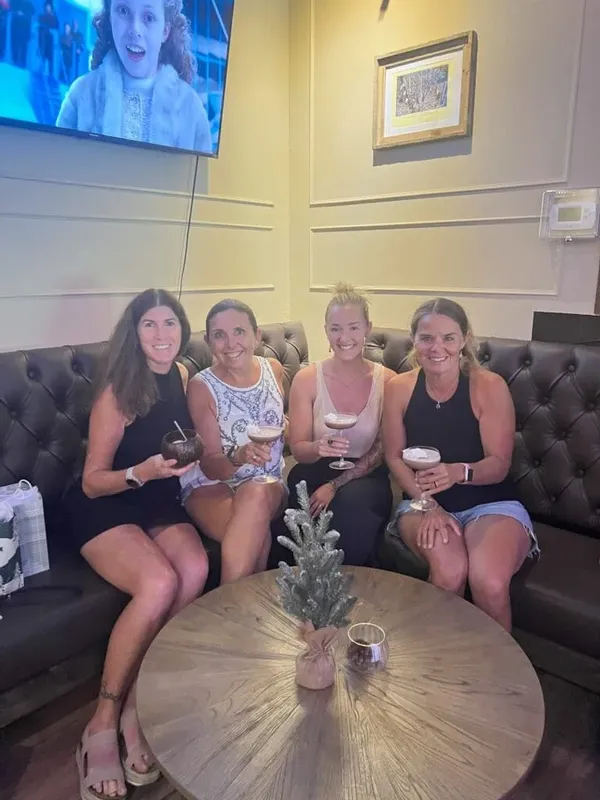Quatre femmes souriantes assises sur un canapé avec des boissons