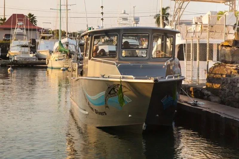 Bateau de plongée amarré dans un port ensoleillé avec des passagers