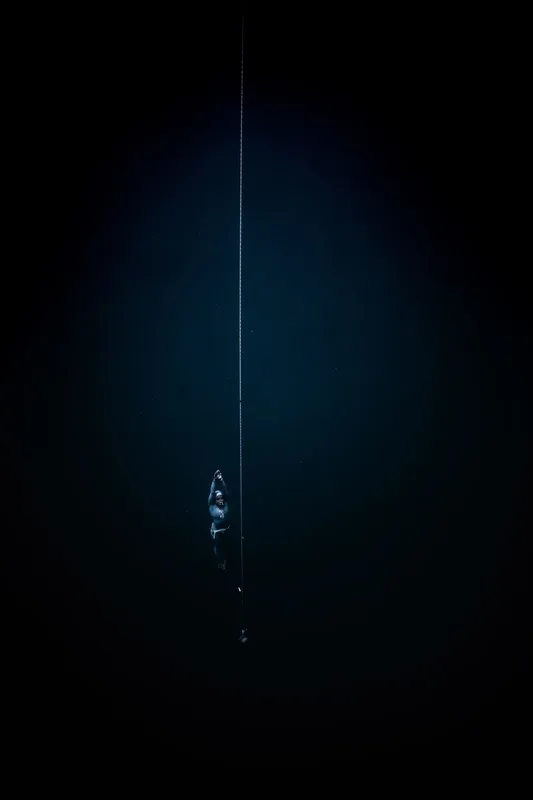Plongeur descendant le long d'une corde dans l'obscurité marine