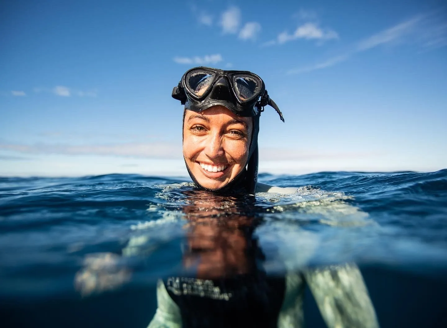 Plongeuse souriante, visage au-dessus de la surface de l'eau, ciel bleu