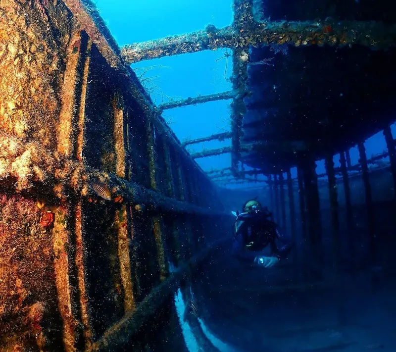 Plongeur explorant l'intérieur d'une épave métallique sous-marine