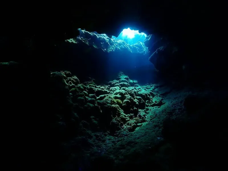 Ouverture dans une paroi rocheuse sous-marine, lumière filtrant à travers l'eau