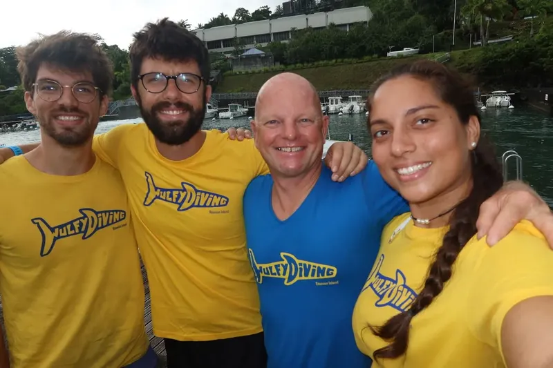 Quatre personnes souriantes posent pour une photo en bord de mer