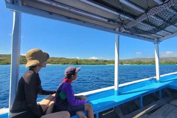 Deux personnes regardent l'horizon depuis un bateau bleu en mer
