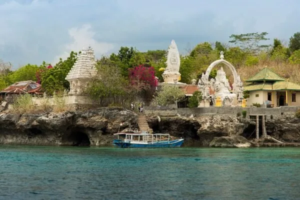 Vue d'un temple balinais en bord de mer avec un bateau amarré