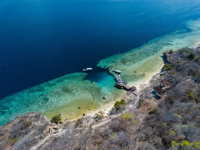 Vue aérienne d'une plage avec bateaux, bâtiments et récifs coralliens