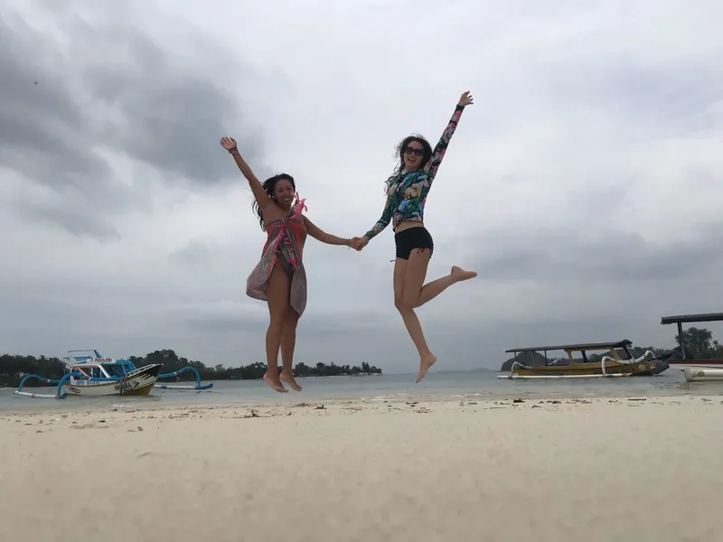 Deux femmes sautent de joie sur une plage ensoleillée