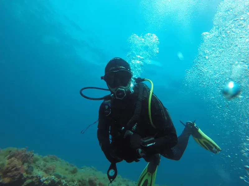Plongeur en combinaison noire nageant dans une eau bleue claire