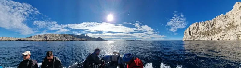 Personnes à bord d'un bateau en mer, paysage rocheux en arrière-plan