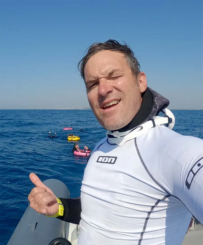 Homme souriant à bord d'un bateau, pouce levé, mer bleue