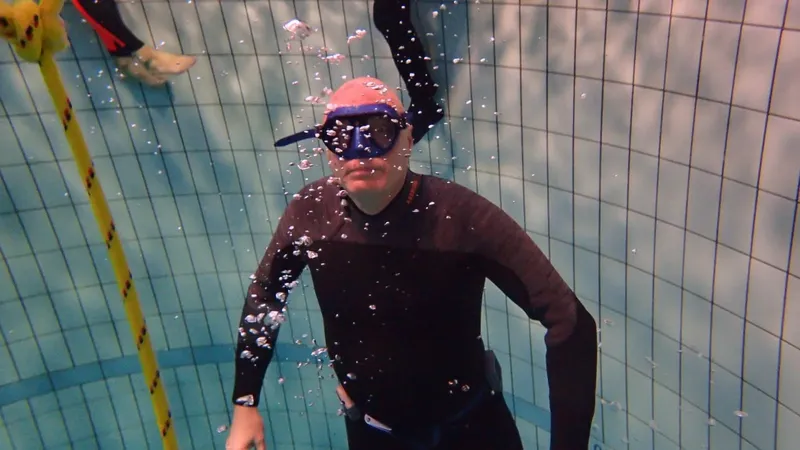 Plongeur en combinaison et masque nageant dans une piscine bleue