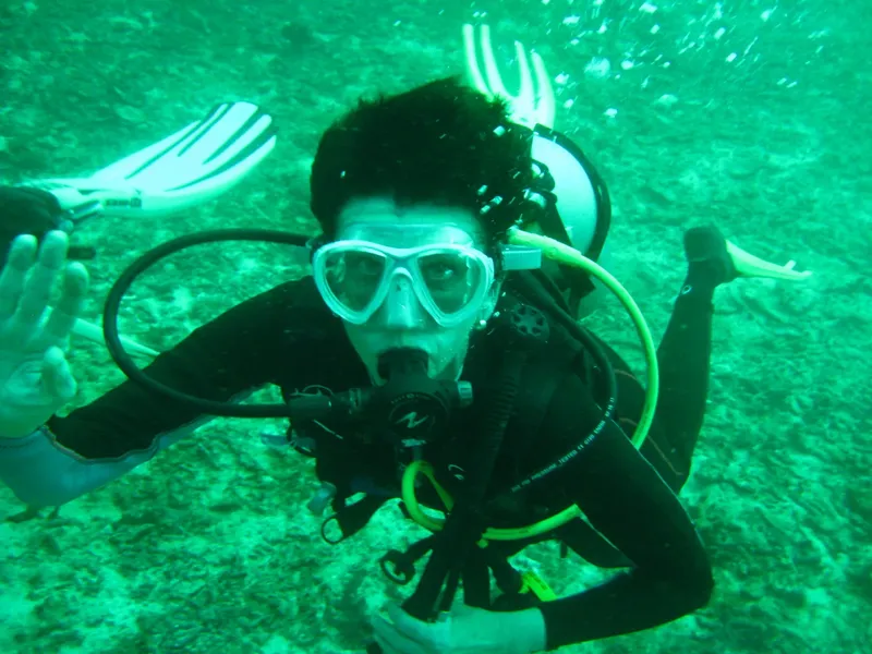 Plongeur souriant avec masque et détendeur dans l'eau verte