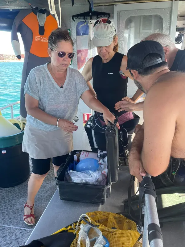 Trois personnes préparent du matériel de plongée sur un bateau en mer