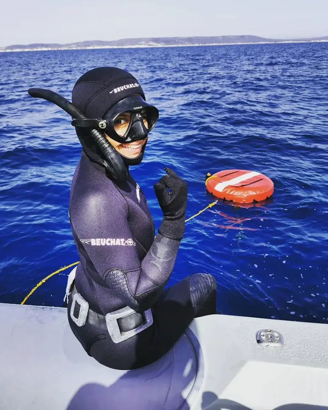 Plongeuse souriante à bord d'un bateau, prête pour l'immersion en mer