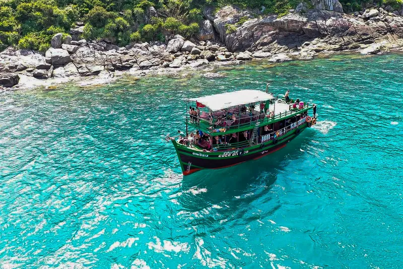 Bateau de plongée coloré navigue sur une mer turquoise ensoleillée