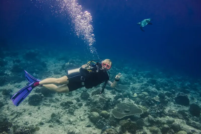 Plongeur souriant avec une tortue de mer en arrière-plan
