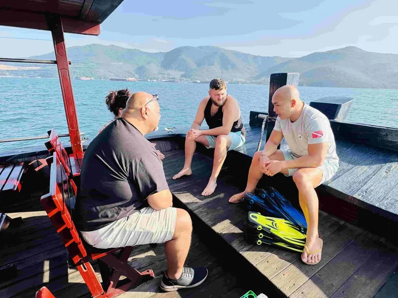 Trois hommes discutent sur le pont d'un bateau de plongée ensoleillé